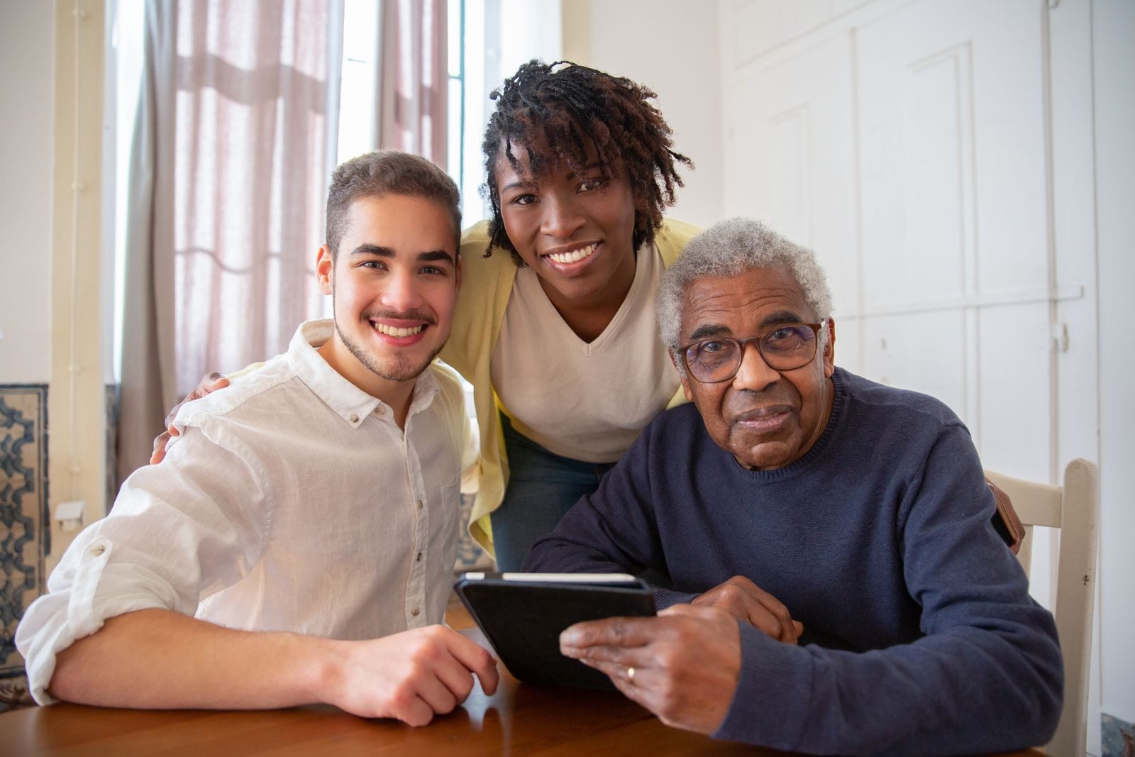 A senior with family members using technology together at home